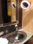 Counter top, transparent basin, illuminated magnifying mirror and a fog-free wall mirror