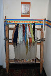 Carpet weaving machine. The coloured threads of silk are hung at the top. You can see a partially weaved carpet at the bottom