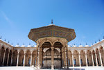 The courtyard of the mosque. In the middle of the courtyard is a marble ablution fountain with a carved wooden roof on columns.