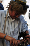 A jewish boy putting on his Tefillin (a pair of black leather boxes containing Hebrew parchment scrolls), one on his head, and one on his arm.