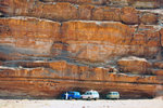 The jeeps were parked under a huge cliff of rocks while the boys were having fun with the dune