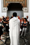 No he is not a priest holding a ceremony, he is only an official tour guide