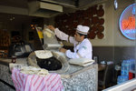 How the bread is made... first dough is being flattened and then pasted to the oven for baking..